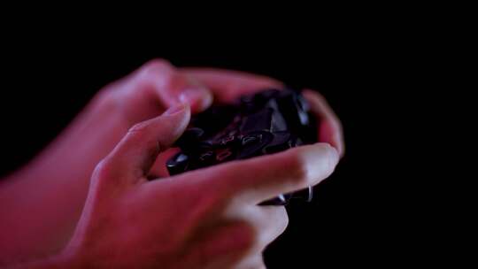 在黑暗的房间里玩电子游戏，黑色背景在一个小控制器按钮上播放