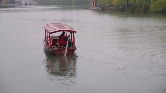 扬州瘦西湖阴雨天在雨中行驶的摇橹船及船娘