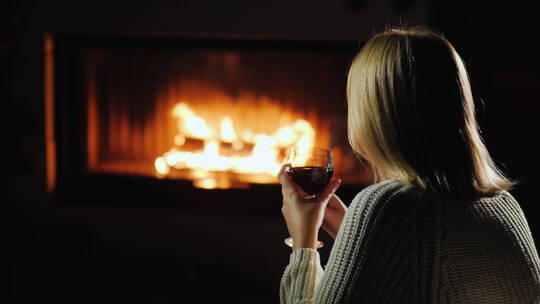 坐在壁炉旁喝红酒的女人