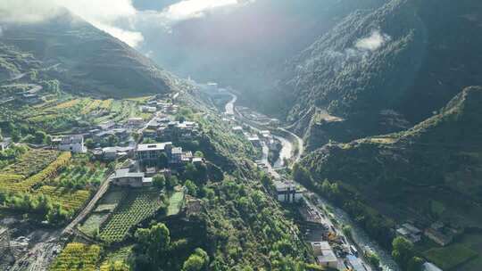 航拍高山之间的峡谷，溪流旁边是村庄电线杆