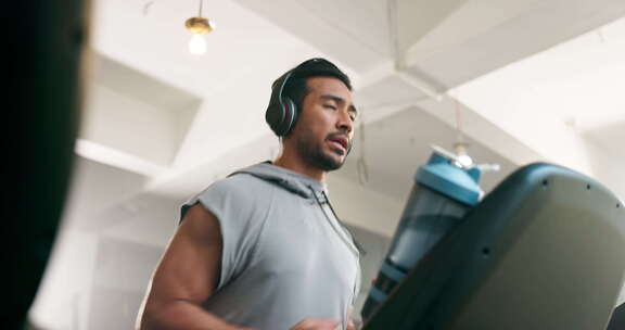 健身，手表和人在跑步机上用耳机在健身房训