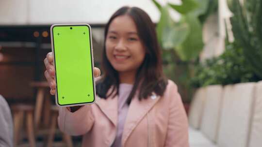 亚洲女人拿着带绿屏模型的智能手机