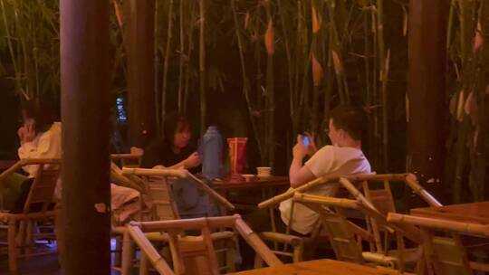夜晚公园竹编椅喝盖碗茶玩手机的人们