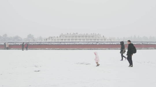 大雪天气中的天坛公园圜丘前经过的一家人