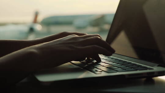 机场窗口的女性手在笔记本电脑上打字视频素材模板下载