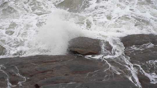 海浪拍打岩石浑浊海水冲刷礁石浪花阴天大海