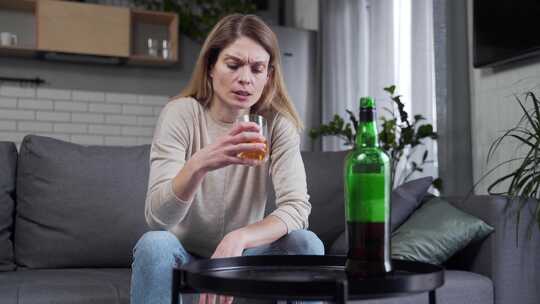 一个成年醉酒女人独自坐在厨房的沙发上喝酒