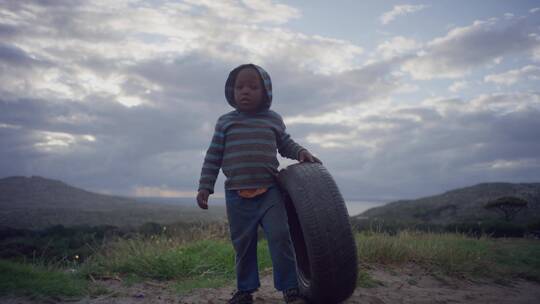 孩子拖着轮胎站在野外