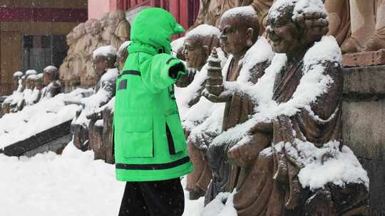 天台山华顶讲寺下雪中小朋友与佛像互动场景