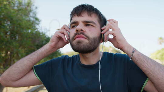 男孩戴着有线耳机在公园户外听音乐