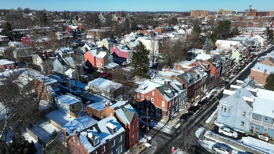 无人机在冬雪中飞越美丽的一排房子。美国郊