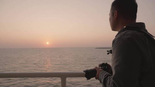 摄影师在轮船甲板上拍摄海上夕阳