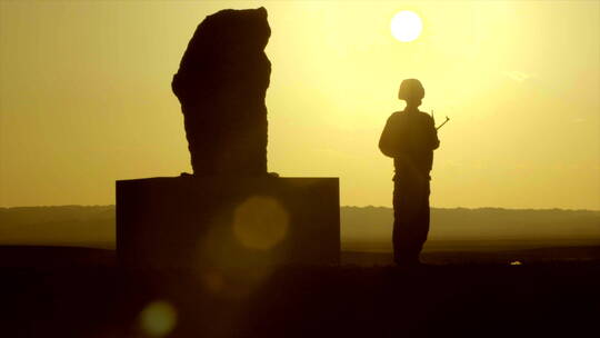 边防战士在石碑前站岗 夕阳 逆光剪影 中景