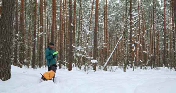 一个自由职业者和他的狗在雪地森林里散步