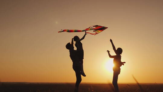 快乐的家庭在日落时玩风筝妈妈爸爸和女儿在一起很开心4K视频