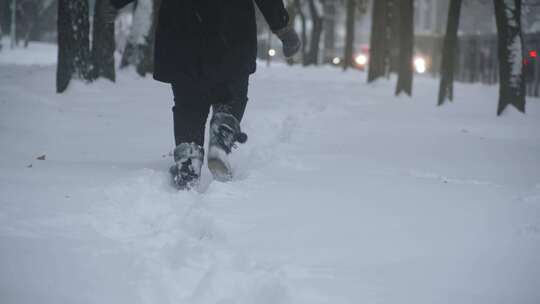 穿着冬衣和靴子的人的腿在深深的雪堆中奔跑