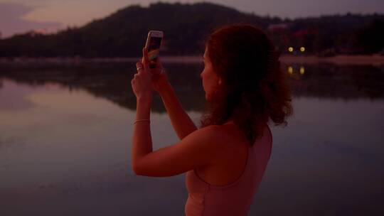 日落时分在海边拍照的女孩