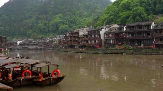 中国凤凰的沱江晨景，有船和传统房屋。向右