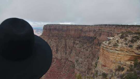 穿着黑色衣服戴着帽子的女人站着眺望大峡谷