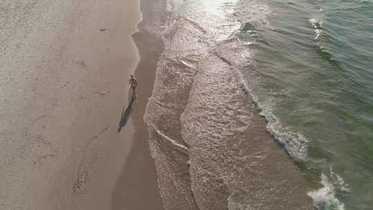 日出时，一名身穿比基尼的美丽女子正在海边散步。美国4k