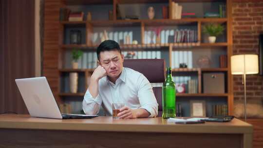 亚洲商人在办公室工作时喝酒。酗酒。员工企