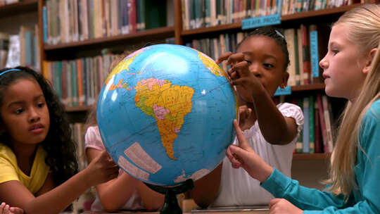 可爱的小女孩在图书馆看地球仪