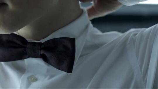 男子纠正他在室内白色夹克上的深色领结