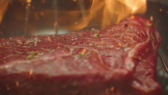 不锈钢烤肉仓库的烤肉牛排，深色背景下着火