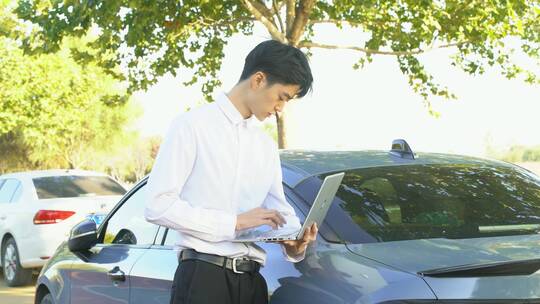 年轻商务男士在户外汽车旁使用电脑