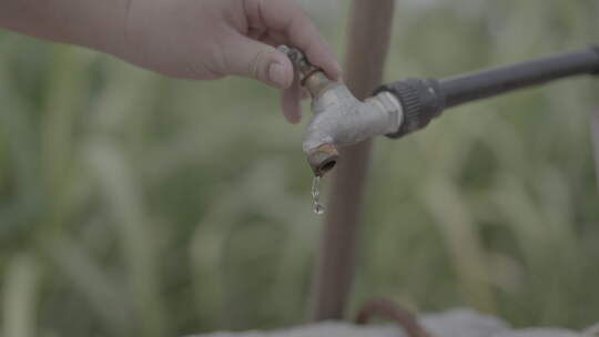 手拧户外水龙头滴水的特写画面