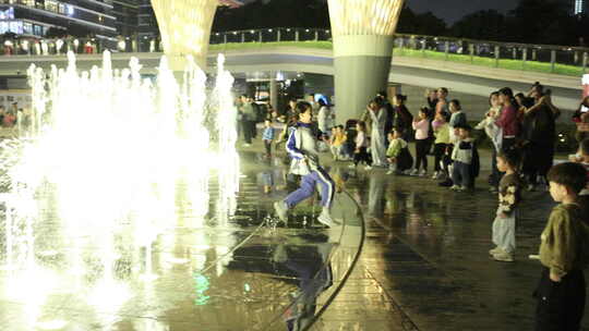 喷泉旁小孩奔跑周围有人围观
