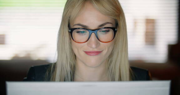 戴着黑框眼镜的女人在办公室阅读电子邮件