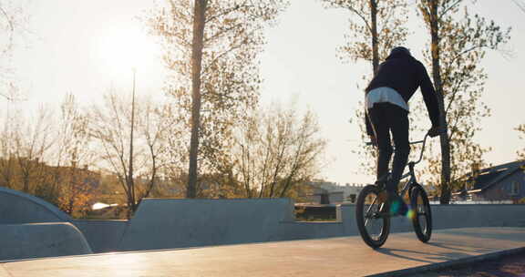 一个年轻人在坡道上的滑板公园拿着一辆Bmx自行车