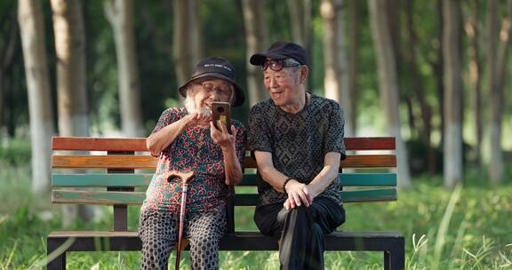 幸福的老年夫妇在公园一起看手机聊天