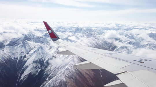 透过飞机舷窗往外看，飞机在雪山和云海上