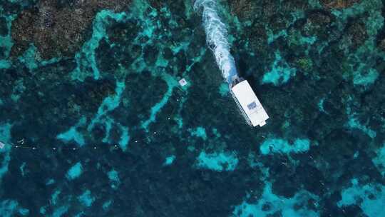 潜水船在热带珊瑚礁系统上空穿过水面的独特景色。高无人机视图
