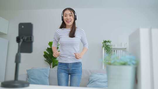 亚洲迷人的女人喜欢在家里的客厅里随着音乐跳舞。