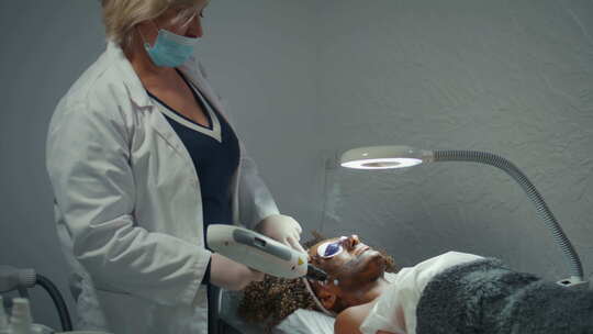 皮肤科医生用碳素面膜做面部脱皮女人躺着眼