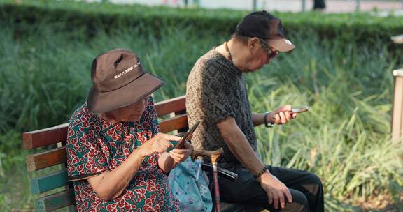 幸福的老年夫妇在公园一起看手机聊天