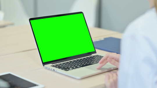 在带有绿色屏幕的笔记本电脑上工作的人