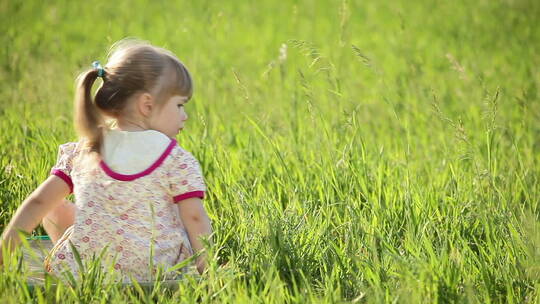 小女孩做在草地上看镜头