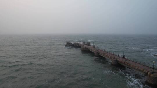 航拍俯瞰威海金海湾饭店冬季风浪中的栈桥