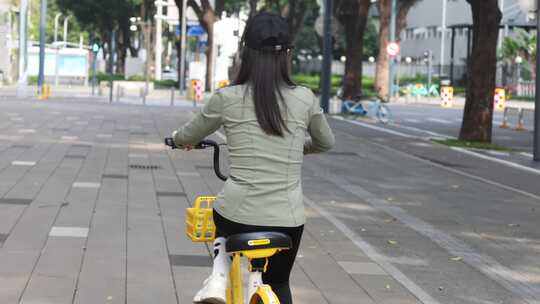 女子城市街道骑行共享单车