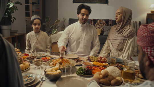 欢快的穆斯林家庭成员在开斋节餐桌上分享食