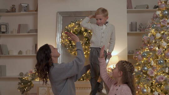 装饰圣诞树后击掌的妈妈和孩子视频素材模板下载