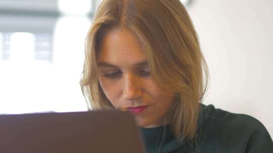 一位创意女性坐在办公桌前的肖像照片。使用笔记本。视频素材模板下载