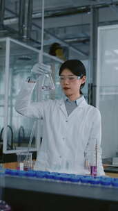 中国女实验室员工检查烧瓶中的液体