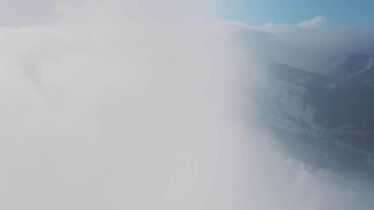 电影无人机在冬季山脉上空的白云中飞行