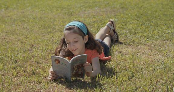 女孩趴在草坪上读书