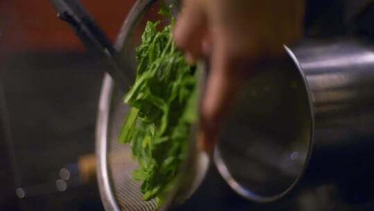 使用金属过滤器和钳子过滤水的绿色蔬菜，拍